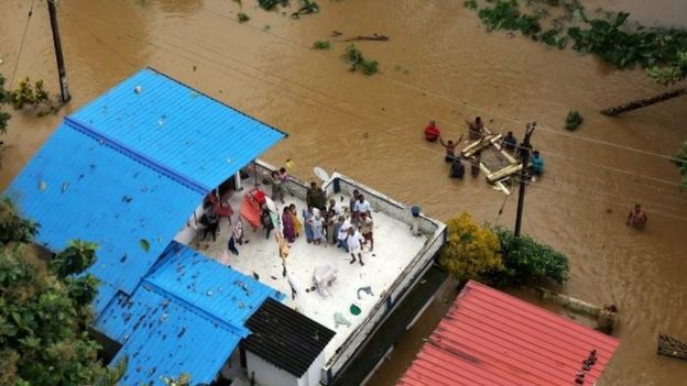 People wait for aid on the roof of their house at a flooded area in the southern state of Kerala, India, on 17 August 2018.