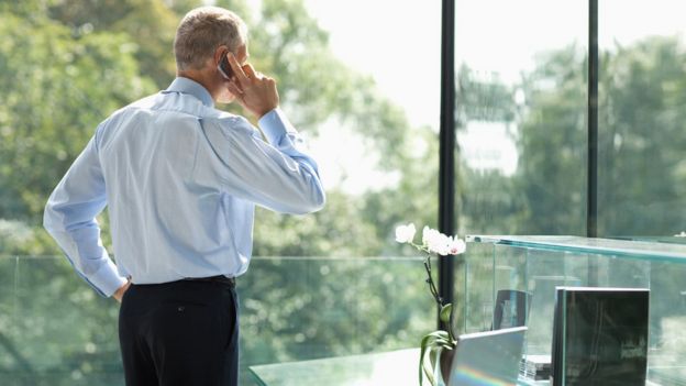 Hombre de negocios mirando por la ventana mientras habla por teléfono