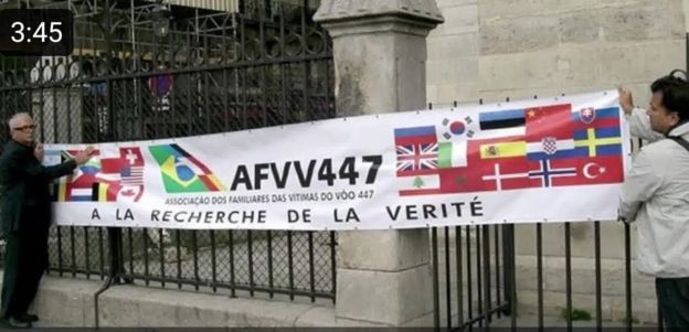 Nelson Marinho e Maarten Van Sluys em frente à Catedral de Notre Dame segurando uma faixa