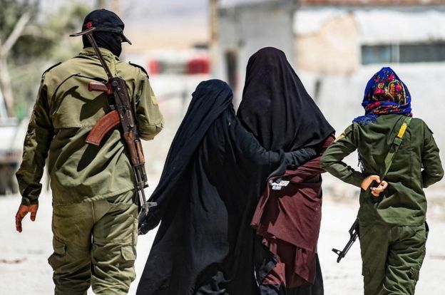 A security patrol escorts women, reportedly wives of Islamic State (IS) group fighters, in the al-Hol camp in north-eastern Syria
