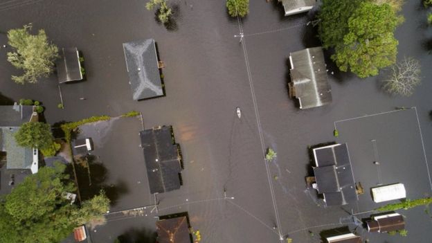 Aerial view of houses, flooding and people paddling in canoes in New Bern