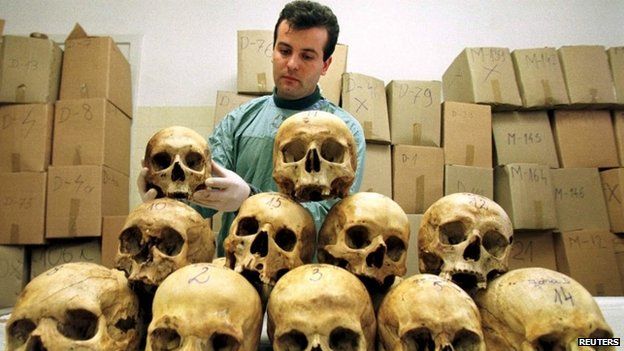 Bosnian pathologist Rifat Kesetovic examines skulls of victims taken from mass graves and in wooded areas following the 1995 massacre