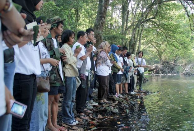 People pray at a riverside memorial service for lost elephants
