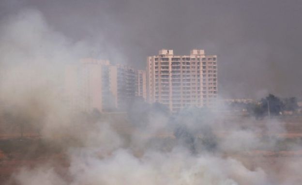 Residential buildings are visible behind the stubble burning smoke at a rice field in Zirakpur in the northern state of Punjab, India, October 10, 2018