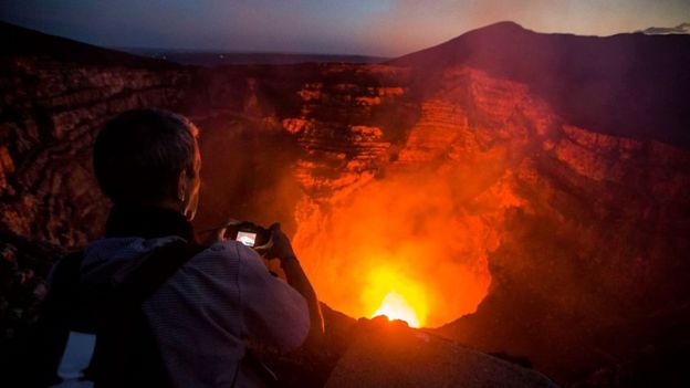 Un turista le toma una foto a la caldera hirviente del volcán Masaya