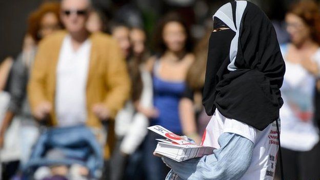 A veiled women hands out leaflets in Switzerland against the banning of face-covering headgear in public places.