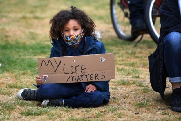 Un niño protesta con una pancarta que dice 