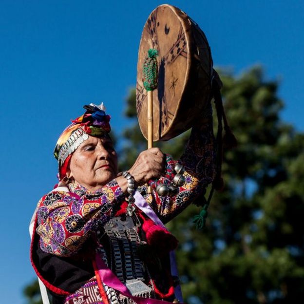 Mulher mapuche, com roupa típica e tocando instrumento