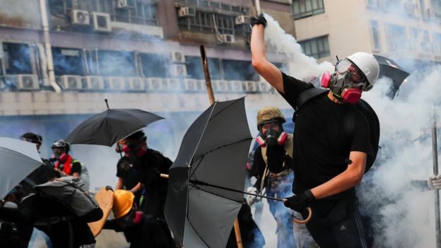 A demonstrator throws back a tear gas canister as they clash with riot police during a protest in Hong Kong, China, August 24, 2019.