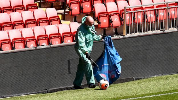A staff member disinfects footballs at Anfield