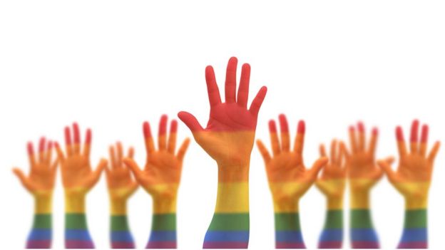 Mãos erguidas e pintadas com cores do arco-íris