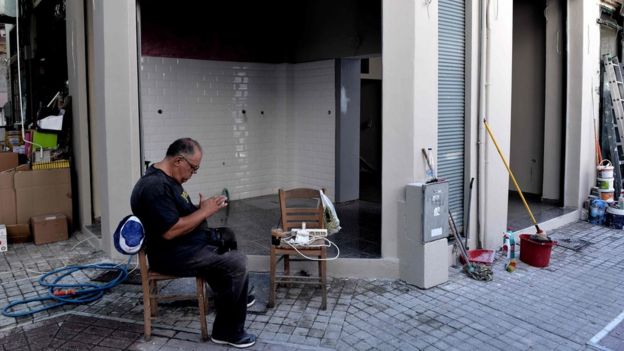 Un hombre sentado frente a su tienda en Thessaloniki