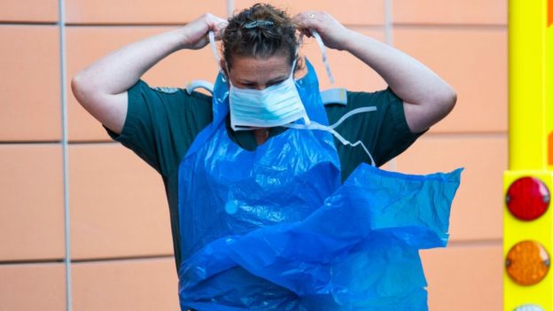 Un trabajador de la salud se coloca equipo protector para la pandemia.