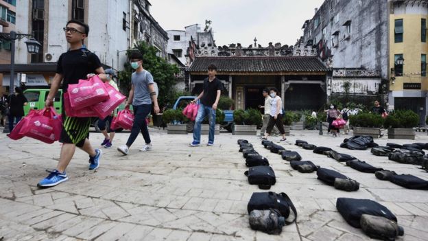 澳门市区内搬运赈灾物资中的本地志愿者走过解放军士兵搁下的个人装备（25/8/2017）