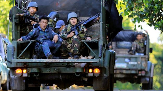 Government soldiers on military vehicles patrol after a continued assault on fighters from the Maute group who have taken over large parts of Marawi city