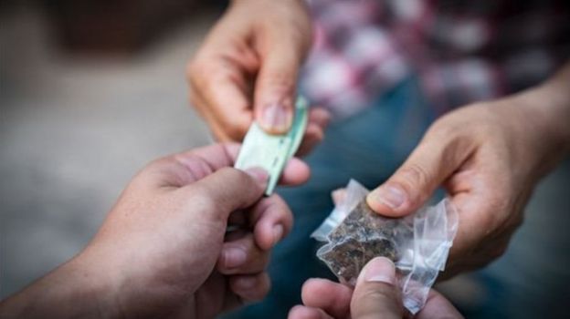 Pessoas fazem transação de compra de drogas