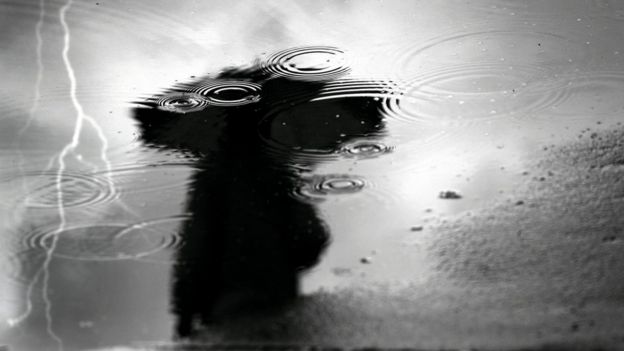 Reflejo de una mujer y rayo en charco de lluvia