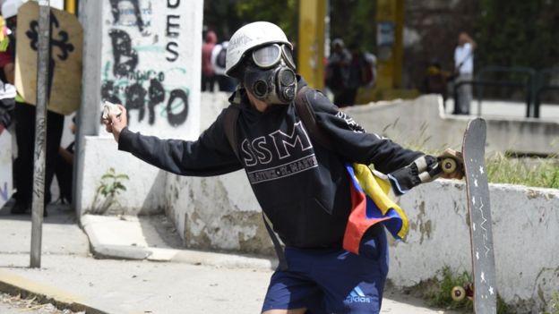 Un manifestante lanza una piedra contra miembros de las fuerzas de seguridad en Venezuela.