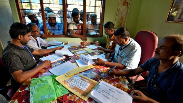 People wait to check their names on the draft list at the National Register of Citizens (NRC) centre at a village in Assam on 30 July 2018