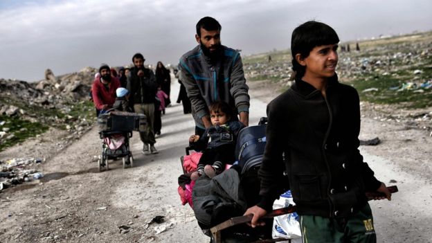 Una familia empuja sus pertenencias en la salida de Mosul.