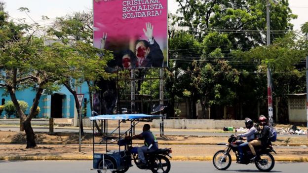 Un letrero semi destruido con los rostros de Daniel Ortega y Rosario Murillo