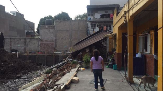 Mujer mirando una estructura derrumbada a causa del terremoto.