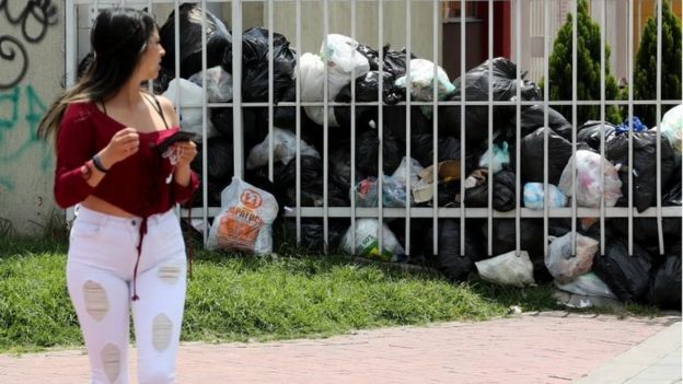 Pedestrians walk by garbage bags in Bogota, Colombia, 07 February 2018