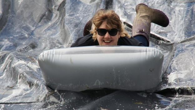 Woman slides down a water slide on an inflatable mattress