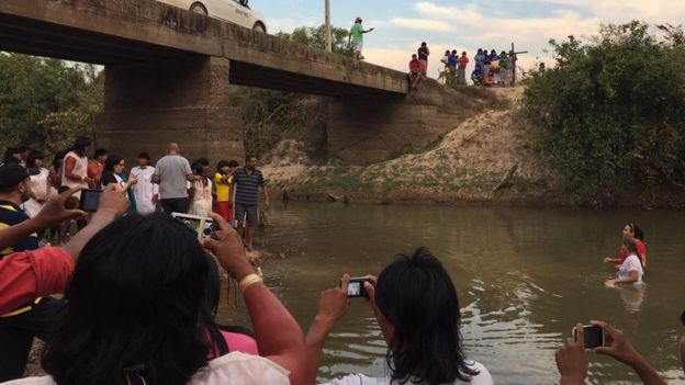 Indígenas em cerimônia de batismo em rio