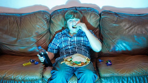 Niño comiendo un plato grande de comida sentado frente a la televisión