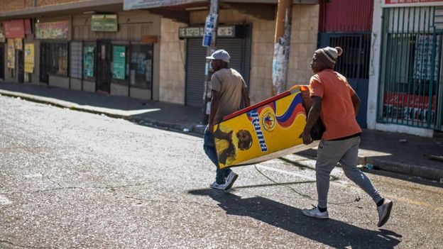 South African looters take a vending machine from an alleged foreign-owned shops during a riot in the Johannesburg suburb of Turffontein