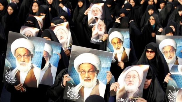 Protesters holding pictures of Sheikh Isa Qassim