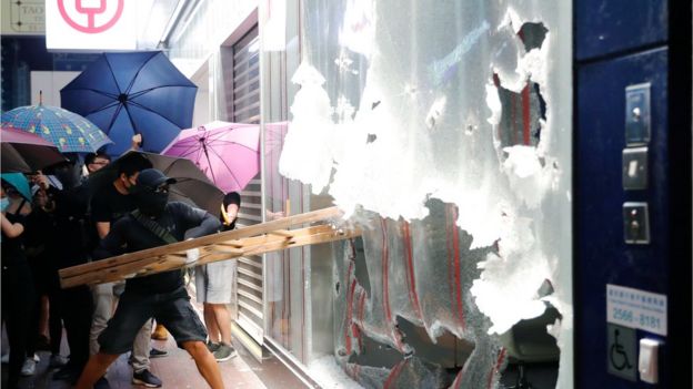 A man smashes the window of a Bank of China branch in Hong Kong with a ladder