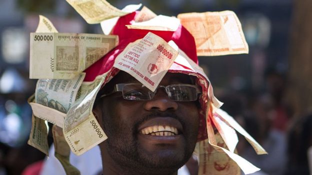 A man wearing a hat decorated with worthless note bearers' cheques during a protest against government plans to introduce bond notes