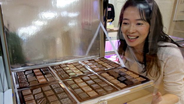 Mulher japonesa observa bandeja de bombons de chocolate