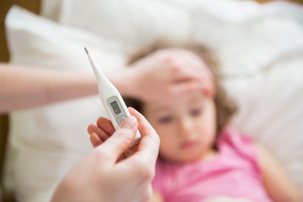 Una madre toma la temperatura de una niña enferma