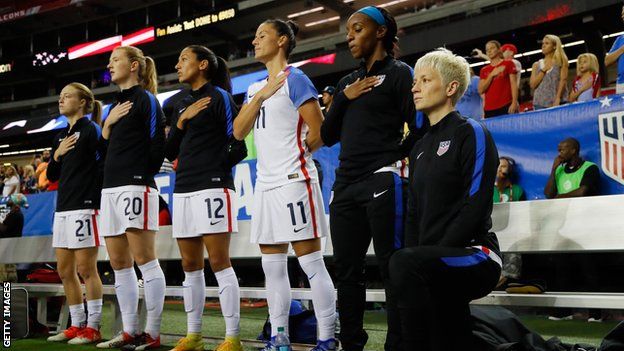 US women's soccer star Megan Rapinoe (right) kneels while team-mates stand during the playing of the national anthem prior to a match