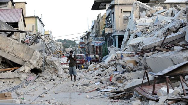 a man covers his face as he walks amid the rubble of a destroyed building in Port-au-Prince on 14 January, 2010