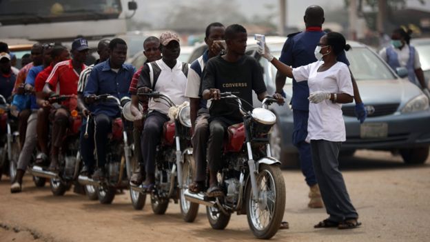 People on motorcycles temperature are measured at a border between Abuja and the Nasarawa State on March 30, 2020,