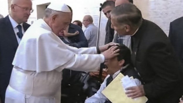 Foto retirada de imagem de TV mostra o Papa com a mão sobre a cabeça de um jovem durante uma missa dominical em um encontro que, dizem alguns, teria sido uma tentativa de exorcismo