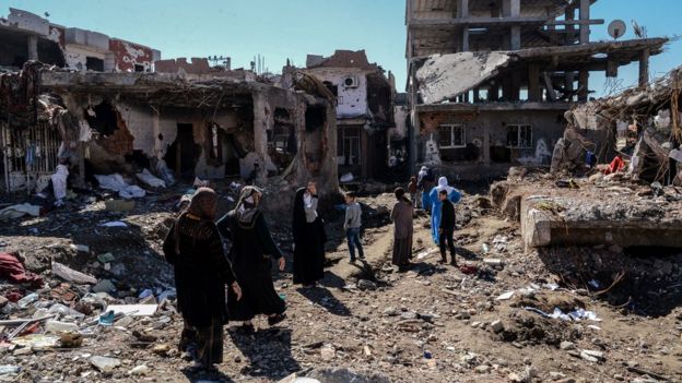 People walk past ruined houses and shops in Cizre, Turkey (8 March 2016)