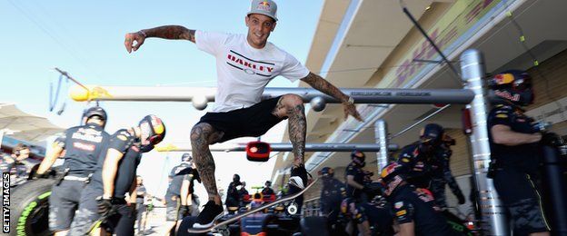 Skateboarder Ryan Sheckler performs a trick in front of the Red Bull Racing team