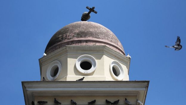 A bird flies past the bell tower of the Church of the Pantanassa