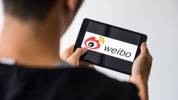 Un hombre sostiene una tableta con el logo de Weibo.