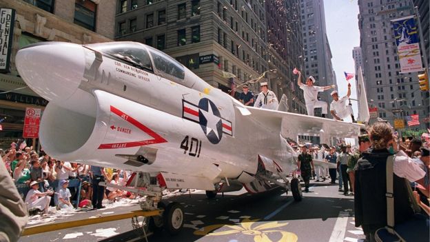 A Navy A-7 Corsair jet is pulled down Broadway Avenue as sailors rejoice on the wings during the Operation Welcome Home ticker-tape parade during the 10 June 1991 celebration for returning Gulf War troops