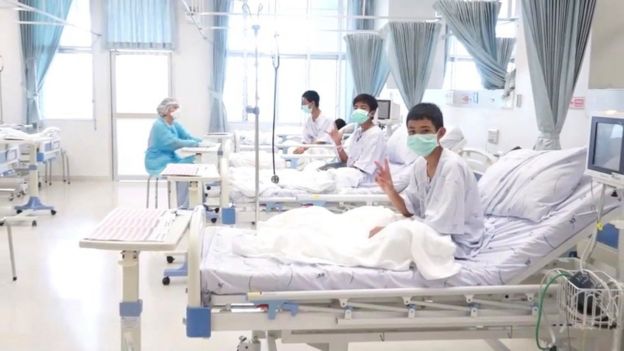 Boys rescued from the cave in Thailand sit up in their hospital beds and give victory signs