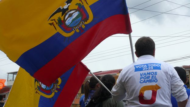 Hombre sostiene una bandera de Ecuador durante la campaña presidencial.