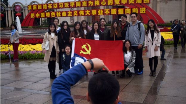 Chinos posan con una bandera del partido comunista