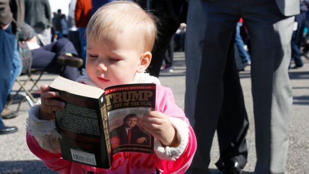 Grace Mahoney, 16 months, looks at a copy of 'The Art of the Deal' before the start of an event with Republican presidential candidate Donald Trump on October 15, 2016 in Portsmouth, New Hampshire.