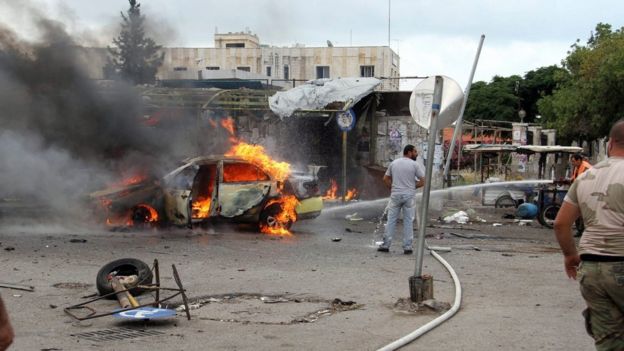 Firefighters tackle burning vehicle following bombing at bus station in coastal city of Tartous, Syria, 23 May 2016